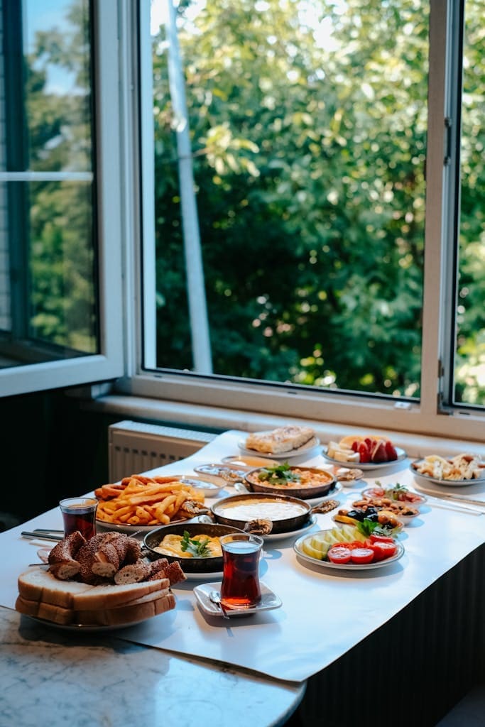 A delicious breakfast spread with various dishes by an open window on a sunny day.